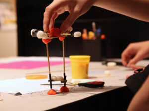 Kind Erstellt Prototyp Mit Knete, Holzstäben, Tape Und Verpackungsmaterialien